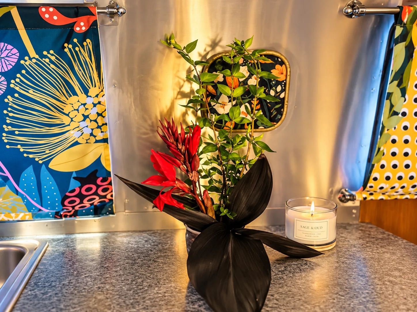 Safari botanical floral arrangement and candle against polished aluminum wall