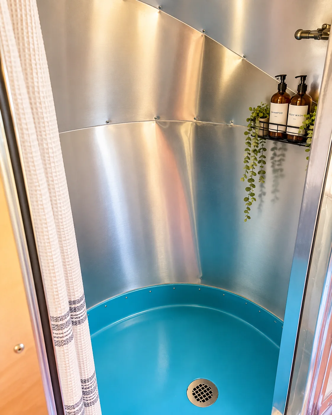 Safari curved shower finished in polished aluminum with blue shower pan